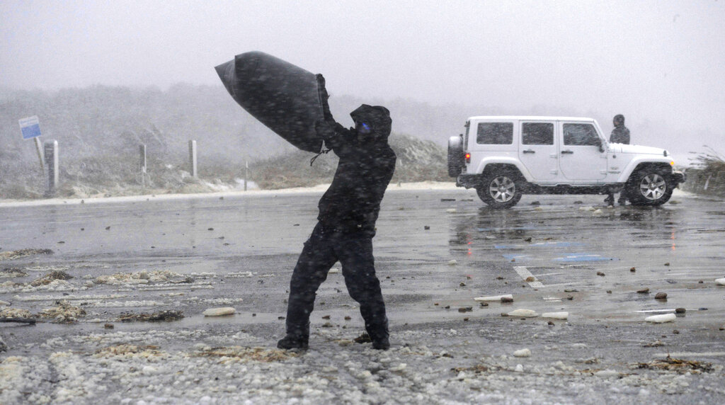 People walk travel through a snowstorm and high winds in West Barnstable, Massachusetts, on Saturday.   