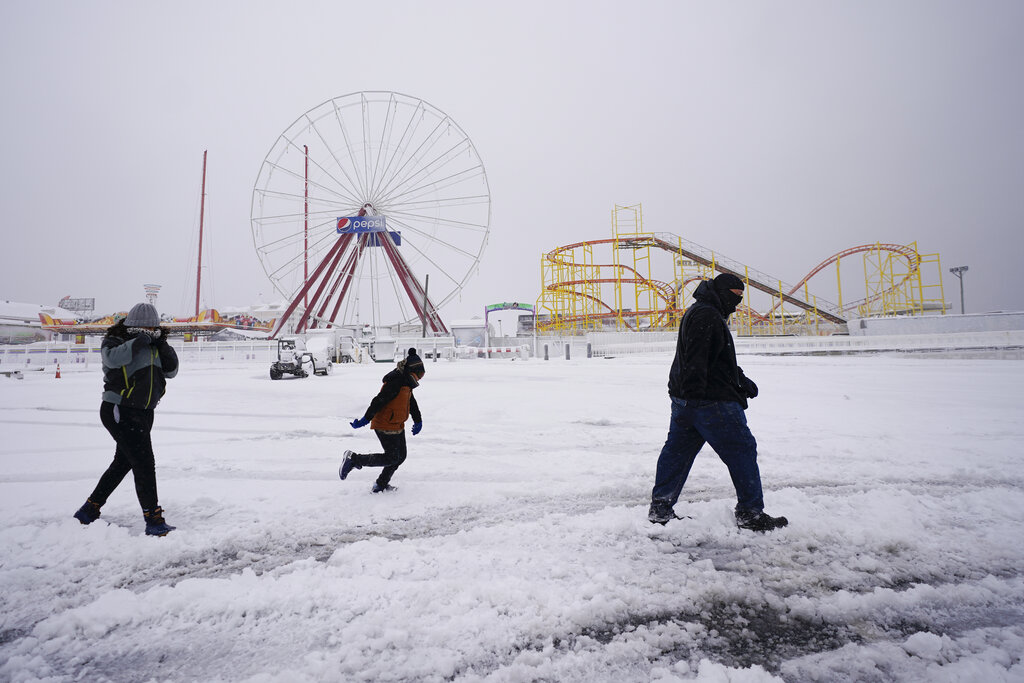 David Bowling walks with his children as they check out the snow near the amusement rides Saturday in Ocean City, Maryland.