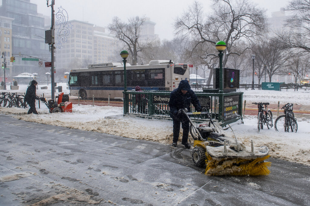 Workers clear sidewalks near Union Square during a snowstorm on Saturday in New York.