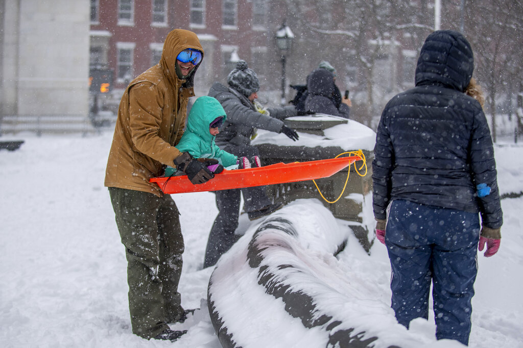 Families play with their children during a snowstorm at Washington Square Park on Saturday in New York. 