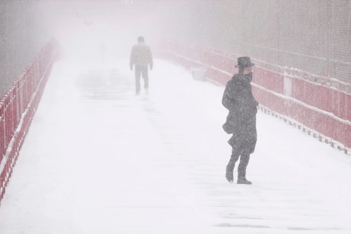 People make their way over the Williamsburg bridge during a snow storm, Saturday, Jan. 29, 2022, in New York. (AP Photo/Mary Altaffer)