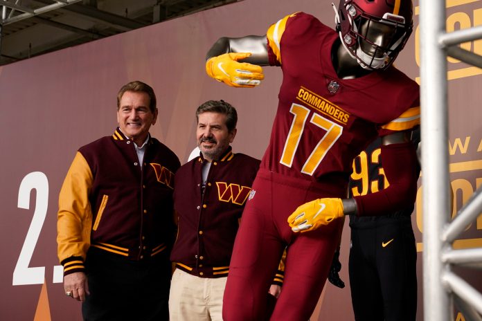 Dan Snyder, right, co-owner and co-CEO of the Washington Commanders, poses for photos with former quarterback Joe Theismann during an event to unveil the NFL football team's new identity, on Feb. 2, 2022, in Landover, Md.