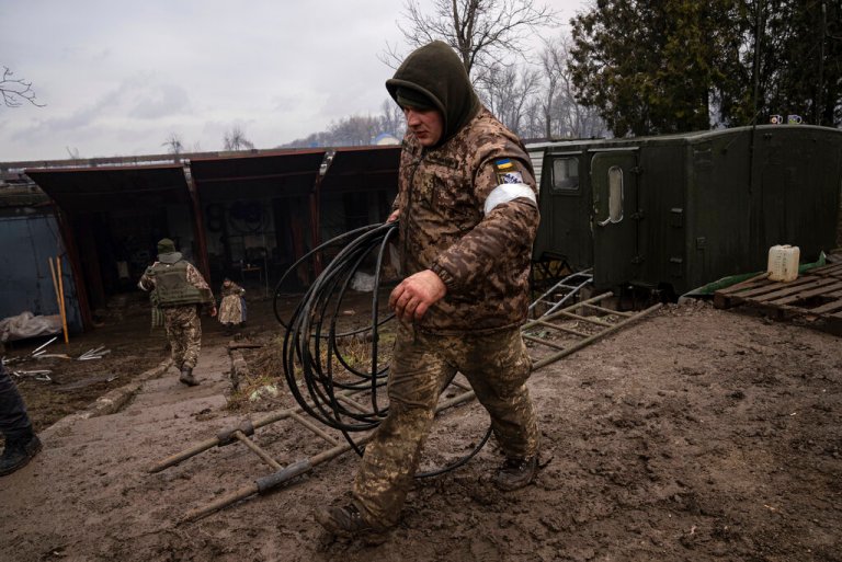 Ukrainian soldiers walk at an air defense base after an apparent Russian strike in Mariupol, Ukraine, Thursday.