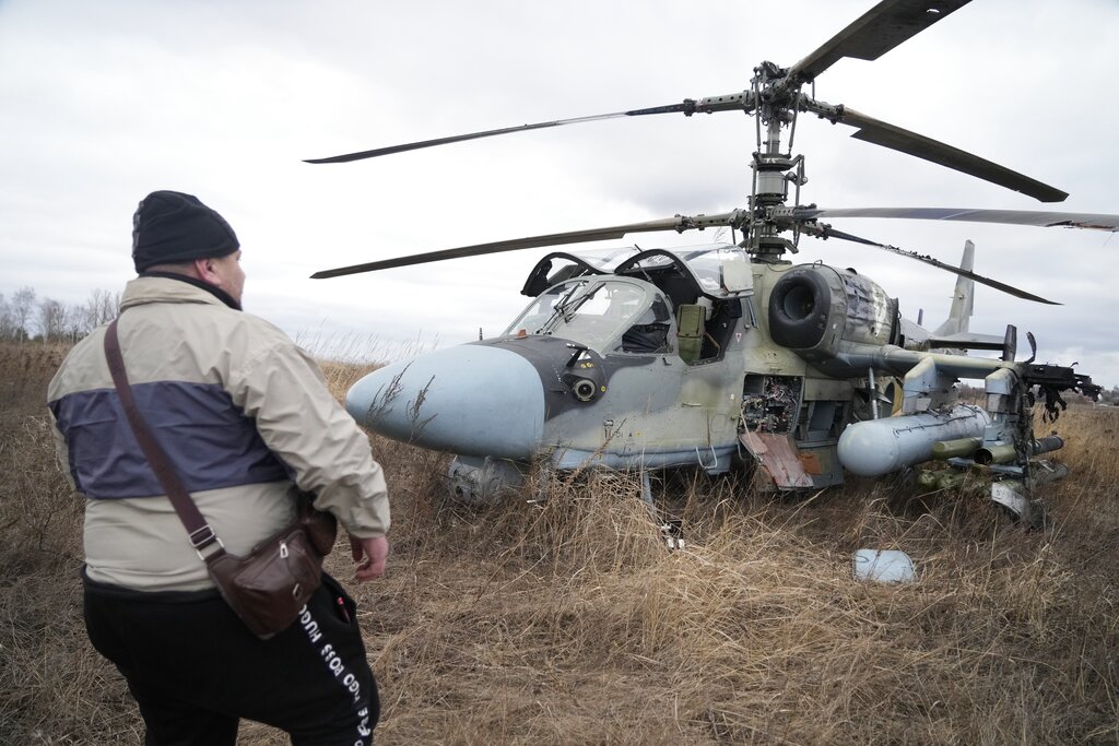 A man stands in front of a Russian Ka-52 helicopter gunship is seen in the field after a forced landing outside Kyiv, Ukraine, Thursday.
