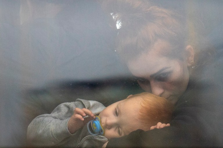 A woman holds her baby inside a bus as they leave Kyiv, Ukraine, Thursday.