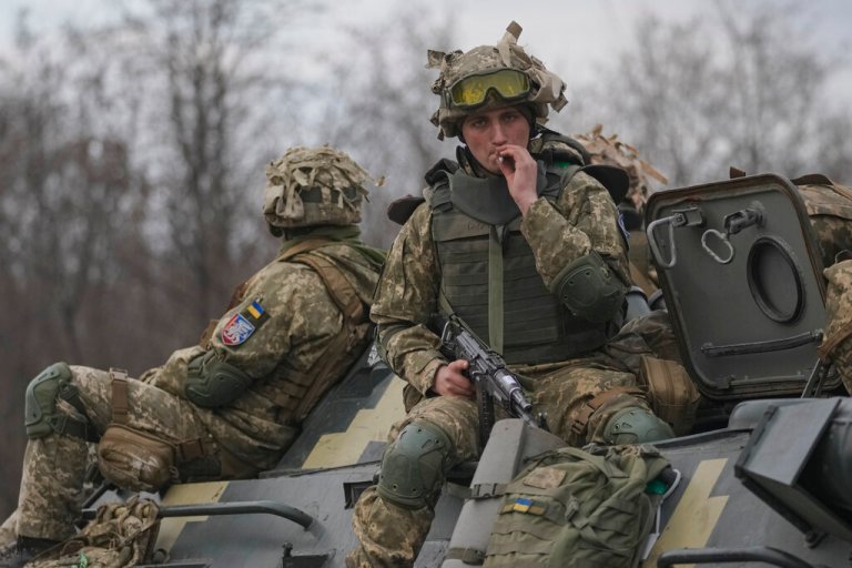 Ukrainian servicemen sit atop armored personnel carriers driving on a road in the Donetsk region, eastern Ukraine, Thursday, Feb. 24, 2022.