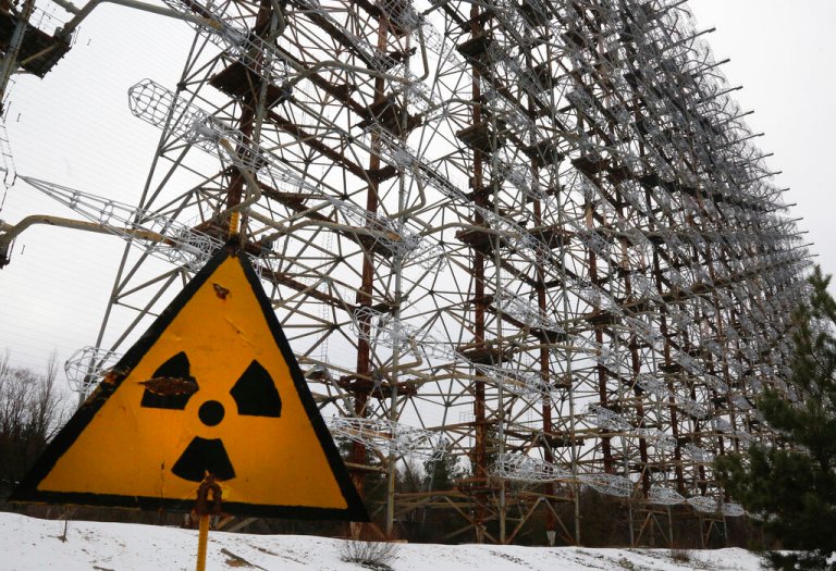 FILE - A Soviet-era top secret object Duga, an over-the-horizon radar system once used as part of the Soviet missile defense early-warning radar network, seen behind a radioactivity sign in Chernobyl, Ukraine, on Nov. 22, 2018.