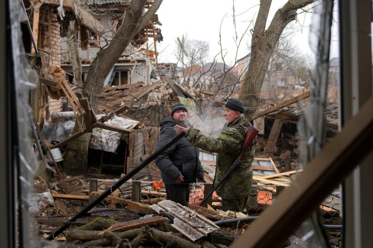 Andrey Goncharuk, 68, right, a member of the territorial defense speaks to a man in the backyard of a house damaged by a Russian airstrike, according to locals, in Gorenka, outside the capital Kyiv, Ukraine, Wednesday, March 2, 2022.  (AP Photo/Vadim Ghirda)