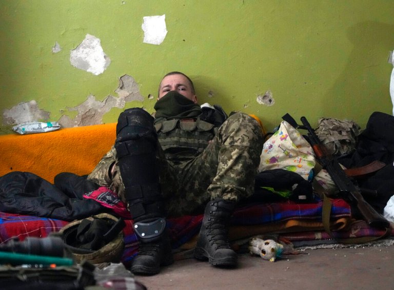 A Ukrainian soldier rests in a basement for shelter in the center of the town of Irpin, northwest of Kyiv, Friday, March 11, 2022.