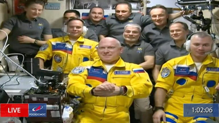 Russian cosmonauts don Ukrainian flag colors as they board space station