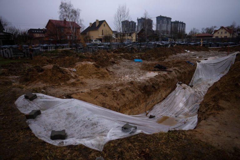 A plastic sheet covers a mass grave with civilians killed during the war against Russia in Bucha, in the outskirts of Kyiv, Ukraine, Sunday, April 10, 2022.