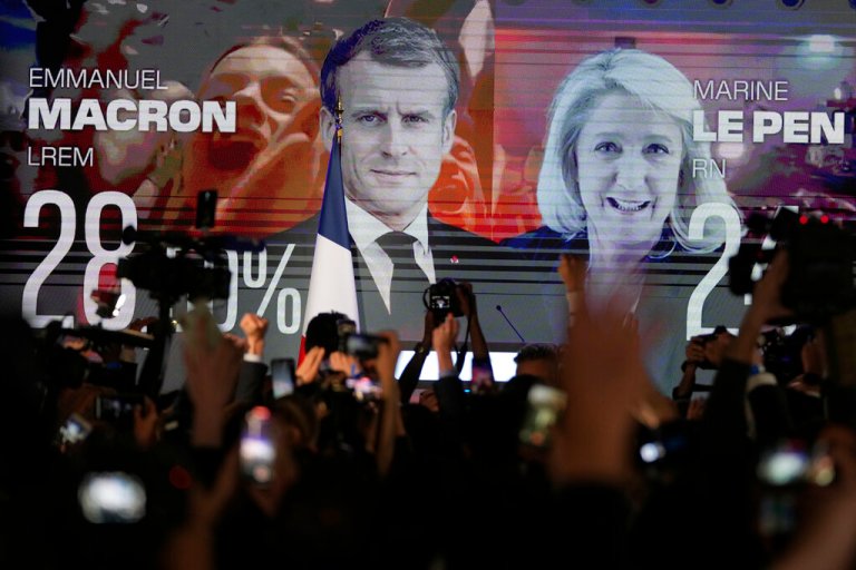 A screen shows French President Emmanuel Macron and centrist candidate for reelection and far-right candidate Marine Le Pen at her election day headquarters, in Paris, Sunday, April 10, 2022.