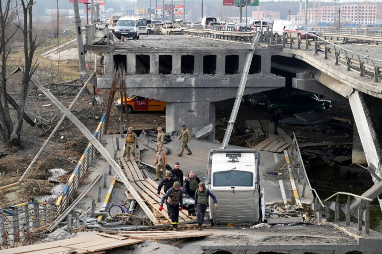 FILE - Ukrainian soldiers carry a body of a civilian killed by the Russian forces over the destroyed bridge in Irpin close to Kyiv, Ukraine.(AP Photo/Efrem Lukatsky, File)