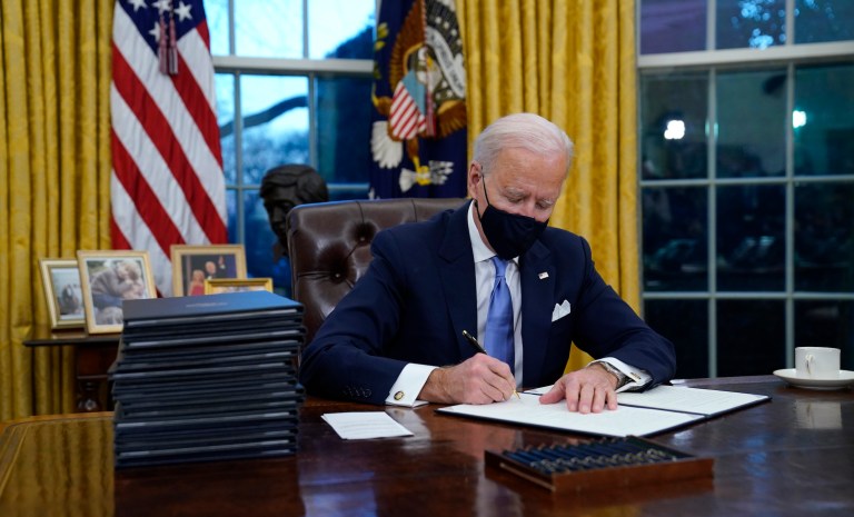 President Joe Biden signs his first executive order in the Oval Office of the White House on Wednesday, Jan. 20, 2021, in Washington.Â 