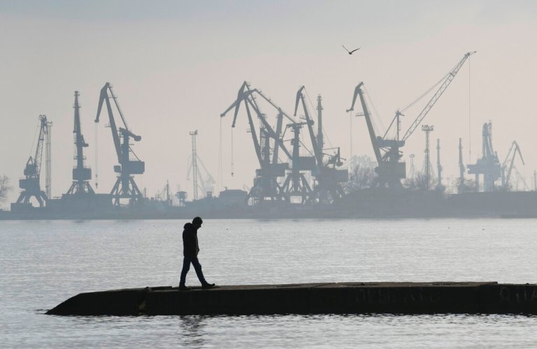 FILE - A man walks with harbor cranes in the background, at the trade port in Mariupol, Ukraine, Wednesday, Feb. 23, 2022. 