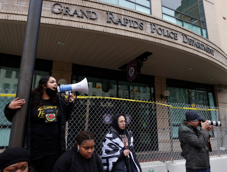 A protester with a bullhorn talks with the crowd in front of the Grand Rapids Police Department during their march in downtown Grand Rapids, Michigan, Saturday, April 16, 2022, in protest of the killing of Patrick Lyoya, a 26-year-old Congolese refugee, by a Grand Rapids police officer on April 4.