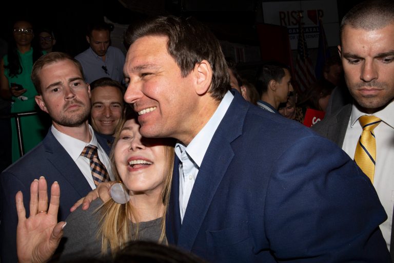 Florida Gov. Ron DeSantis poses for photos with an attendee while Nevada Republican U.S. Senate candidate Adam Laxalt smiles in the background during a rally for Laxalt at Stoney's Rockin' Country on Wednesday, April 27, 2022, in Las Vegas. 