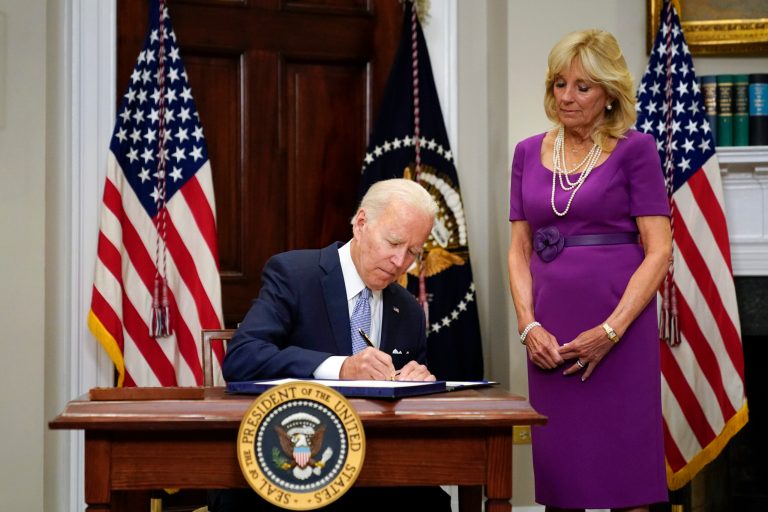 President Joe Biden signs into law S. 2938, the Bipartisan Safer Communities Act gun safety bill, in the Roosevelt Room of the White House in Washington, Saturday, June 25, 2022. First lady Jill Biden looks on at right. 
