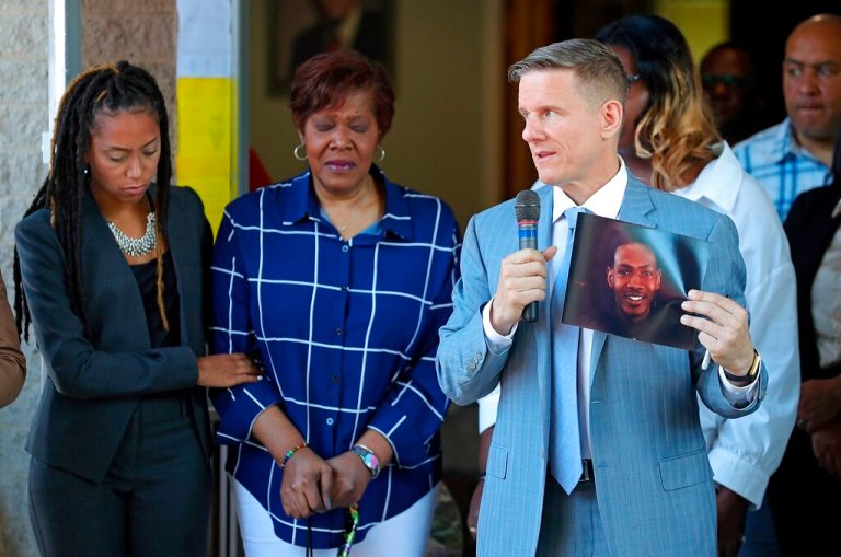 Attorney Bobby DiCello, right, holds up a photograph of Jayland Walker as attorney Paige White, left, comforts Jayland's mother Pamela Walker during a news conference at St. Ashworth Temple, Thursday, June 30, 2022, in Akron, Ohio.  Walkler, shot and killed by police following a vehicle and foot pursuit this week died from multiple gunshot wounds, and his death has been ruled a homicide, authorities announced Wednesday.