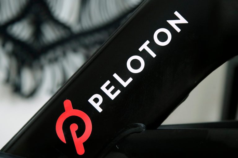 FILE - This Nov. 19, 2019 photo shows a Peloton logo on the company's stationary bicycle in San Francisco, Calif. Peloton announced Friday it is cutting nearly 800 jobs, raising prices for its Bike+ and Tread machines, and outsourcing functions such as equipment deliveries and customer service to outside companies. (AP Photo/Jeff Chiu, File)