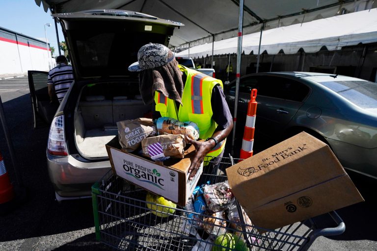 A volunteer fills up a vehicle with food boxes at the St. Mary's Food Bank Wednesday, June 29, 2022, in Phoenix.