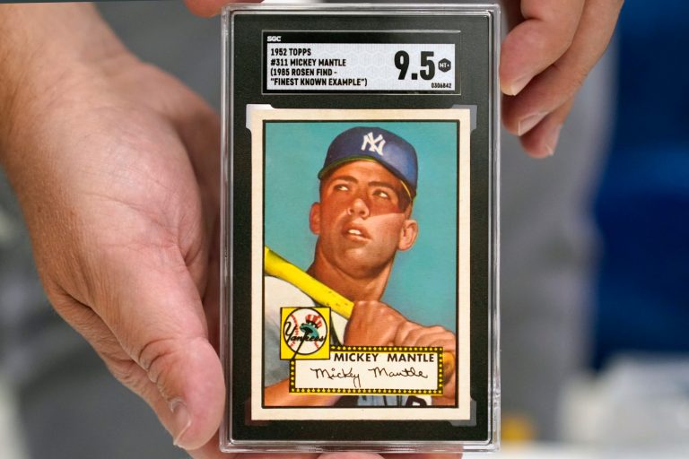 Chris Ivy, director of sports auctions with Heritage Auctions, holds a mint-condition Mickey Mantle baseball card ahead of the end of bidding that led to the record-breaking sale price of $12.6 million, the most ever paid for a piece of sports memorabilia.  