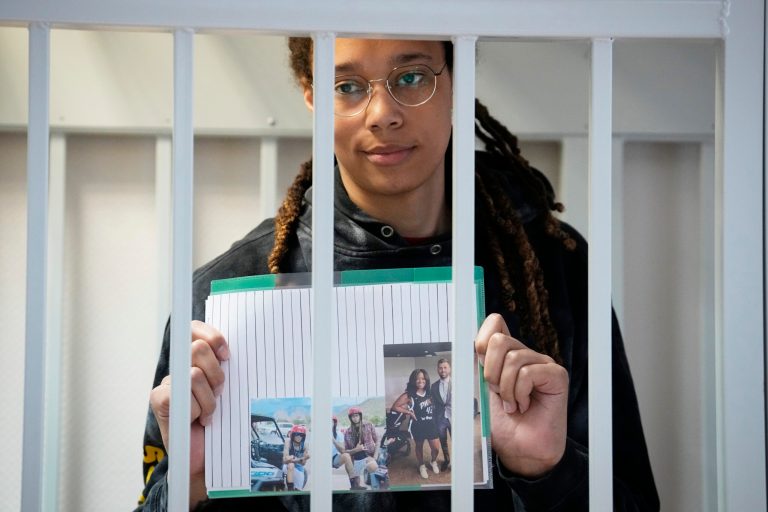 WNBA star and two-time Olympic gold medalist Brittney Griner holds photos while standing in a cage at a Russian court room prior to a hearing, in Khimki just outside Moscow, Tuesday, July 26, 2022.