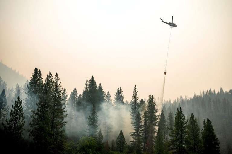 A helicopter drops water on a hot spot while battling the McKinney Fire.