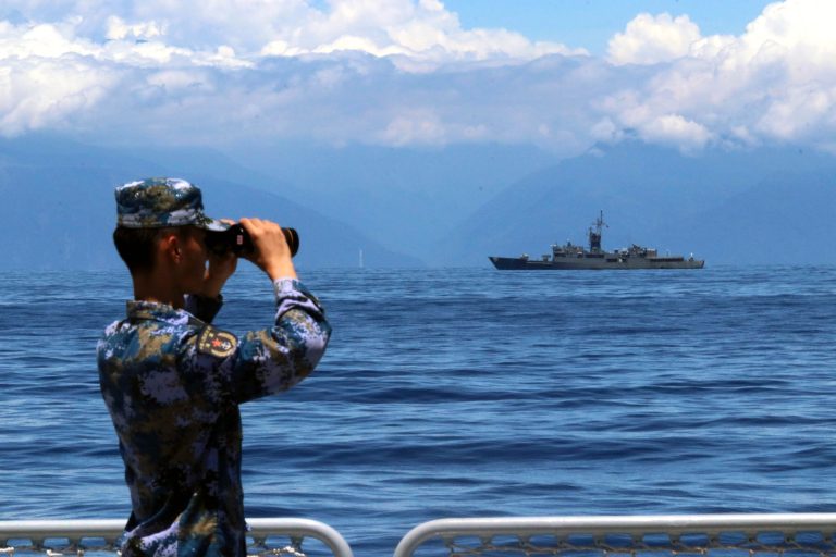 In this photo provided by Chinaâs Xinhua News Agency, a People's Liberation Army member looks through binoculars during military exercises as Taiwanâs frigate Lan Yang is seen at the rear, on Friday, Aug. 5, 2022.