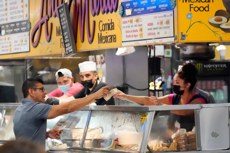 Money is exchanged at a food stand inside Grand Central Market in Los Angeles.