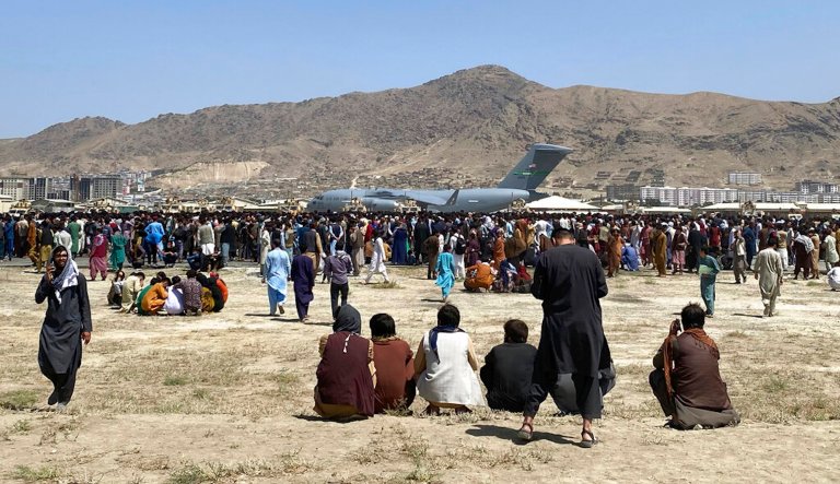 Hundreds of people gather near a U.S. Air Force C-17 transport plane at the perimeter of the international airport in Kabul, Afghanistan, on Aug. 16, 2021. 