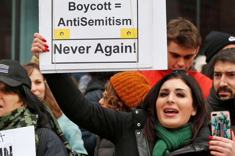 FILE - Nationally known far-right activist Laura Loomer holds up a sign across the street from a rally organized by Women's March NYC, Jan. 19, 2019, after she barged onto the stage interrupting Women's March NYC director Agunda Okeyo who was speaking during a rally in New York. (AP Photo/Kathy Willens, File)