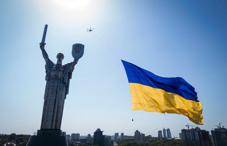A drone carries a big national flag in front of Ukraine's the Motherland Monument in Kyiv, Ukraine, on Aug. 24, 2022.