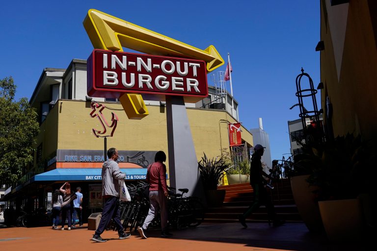 Pedestrians walk below an In-N-Out Burger restaurant sign in San Francisco, Thursday, Aug. 25, 2022. (AP Photo/Jeff Chiu)