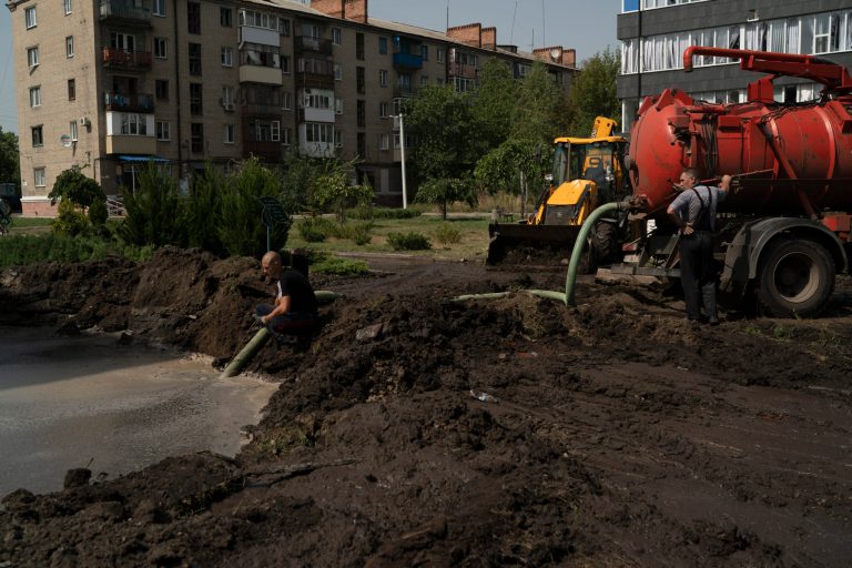 Workers drain water from a crater created by an explosion that damaged a residential building after a Russian attack in Slovyansk, Ukraine, Sunday, Aug. 28, 2022.