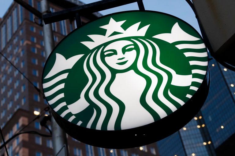 FILE - A Starbucks sign hangs outside a Starbucks coffee shop in downtown Pittsburgh on June 26, 2019. The coffee chain and furniture outlet Ikea will both be offering electric vehicle charging stations as a means to allow people to charge their cars while they rest and recover themselves. (AP Photo/Gene J. Puskar, File)