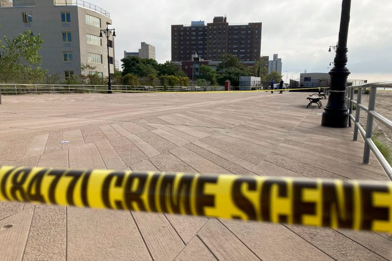 Crime scene tape stretches across a section of the Coney Island boardwalk near a stretch of beach where three children were found dead in the surf.