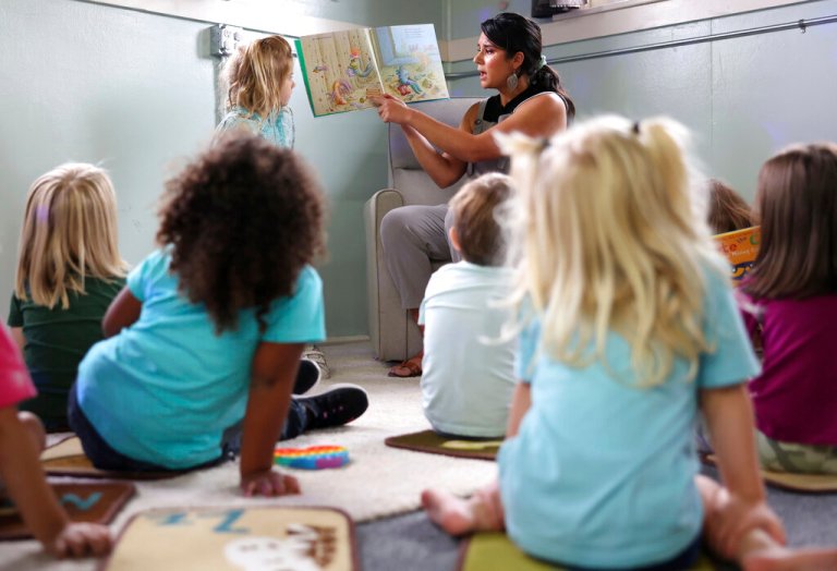 Kiera Holthusen reads a book at Bumble Art Studio day care center in Astoria, Ore., Friday, Sept. 2, 2022. From Oregon to New York, demand for child care far exceeds supply. Families are growing increasingly desperate as providers deal with staffing shortages exacerbated by the coronavirus pandemic as well as historically low pay worsened by inflation.
