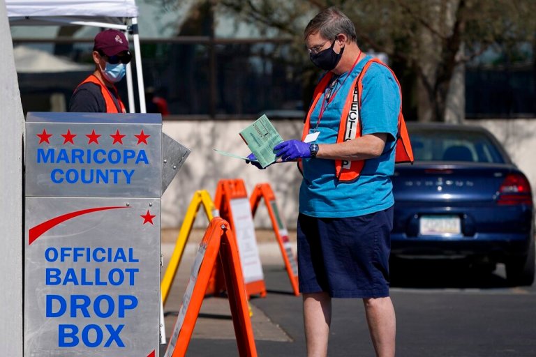 FILE - In this Tuesday, Oct. 20, 2020, file photo, volunteers help voters as voters drop off their ballots at the Maricopa County Recorder's Office in Phoenix. (AP Photo/Ross D. Franklin, File)