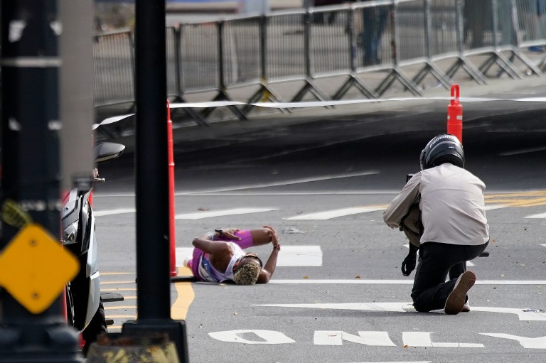 Daniel Do Nascimento, of Brazil, left, lays on the pavement after collapsing in the Bronx borough during the New York City Marathon, Sunday, Nov. 6, 2022, in New York. 