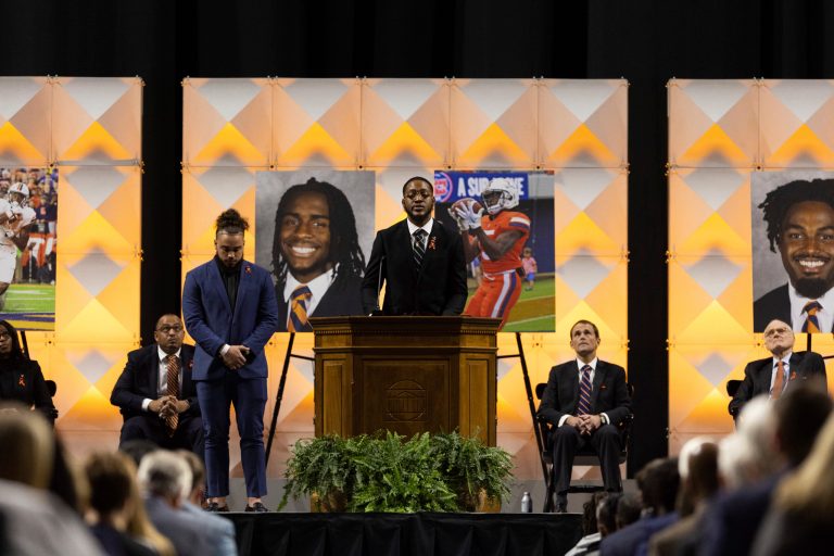 A football player speaks to a crowd during a memorial service in Charlottesville, Va., Saturday, Nov. 19, 2022.