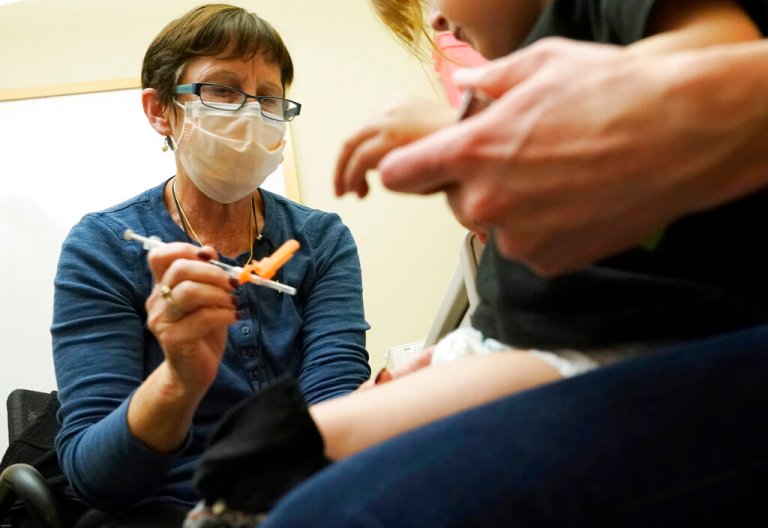 Deborah Sampson, left, a nurse at a University of Washington Medical Center clinic in Seattle, gives a Pfizer COVID-19 vaccine shot to a 20-month-old child, June 21, 2022, in Seattle. 