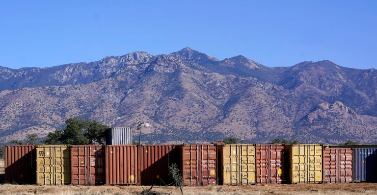 A long row of shipping containers wait for installation along the border where hundreds shipping containers create a wall between the United States and Mexico in San Rafael Valley, Ariz., Thursday, Dec. 8, 2022.
