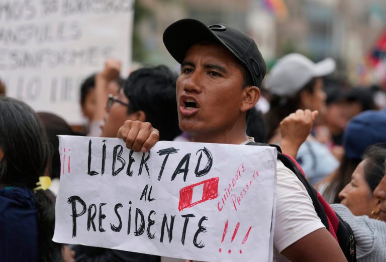 A supporter of ousted Peruvian President Pedro Castillo holds a poster with a message that reads in Spanish: 