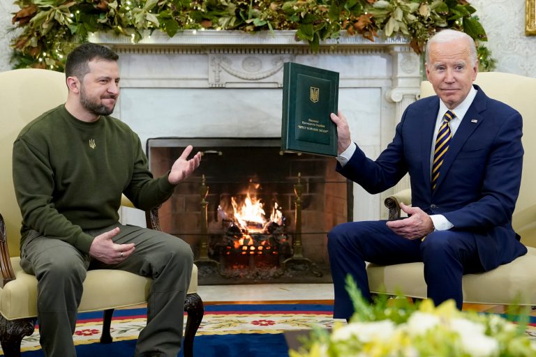 President Joe Biden holds a gift he received from Ukrainian President Volodymyr Zelensky as they meet in the Oval Office of the White House, Wednesday, Dec. 21, 2022, in Washington.
