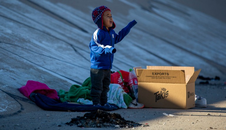 A migrant child cries to get the attention of his father while the family waits in the southern bank of the Rio Grande to cross into El Paso, Texas, from Ciudad Juarez, Mexico, on Wednesday, Dec. 21, 2022.