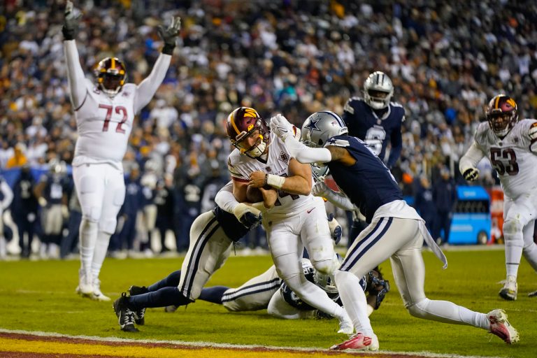 Washington Commanders quarterback Sam Howell (14) scores a touchdown against Dallas Cowboys cornerback Trevon Diggs (7) during the second half an NFL football game, Sunday, Jan. 8, 2023, in Landover, Md.