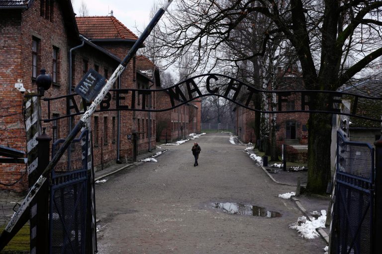 A man walks next to the ''Arbeit Macht Frei