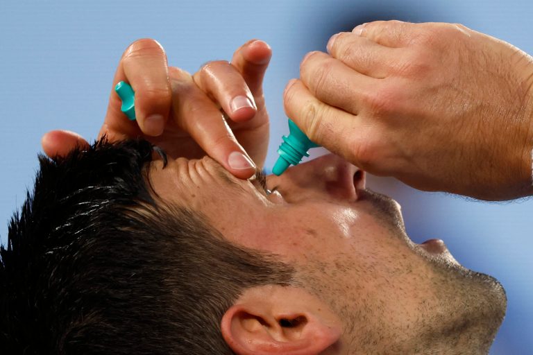 Novak Djokovic of Serbia puts eye drops in his eyes during a break in his semifinal against Tommy Paul of the U.S. at the Australian Open tennis championship in Melbourne, Australia, Friday, Jan. 27, 2023.