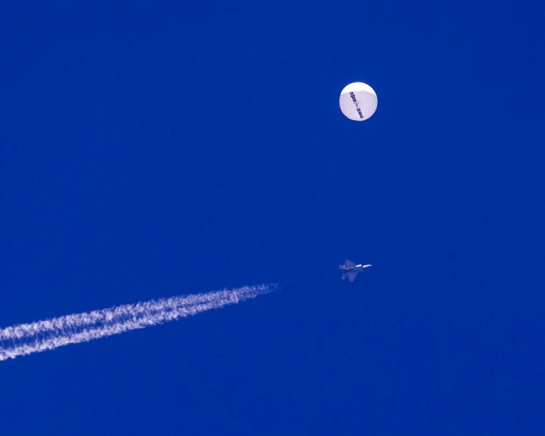 In this photo provided by Chad Fish, a large balloon drifts above the Atlantic Ocean, just off the coast of South Carolina, with a fighter jet and its contrail seen below it, Saturday, Feb. 4, 2023. The balloon was struck by a missile from an F-22 fighter just off Myrtle Beach, fascinating sky-watchers across a populous area known as the Grand Strand for its miles of beaches that draw retirees and vacationers.  